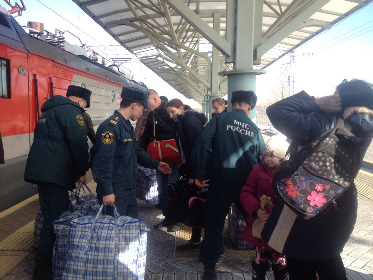  люди з України прибувають потягом і їх зустрічають працівники МНС Росії