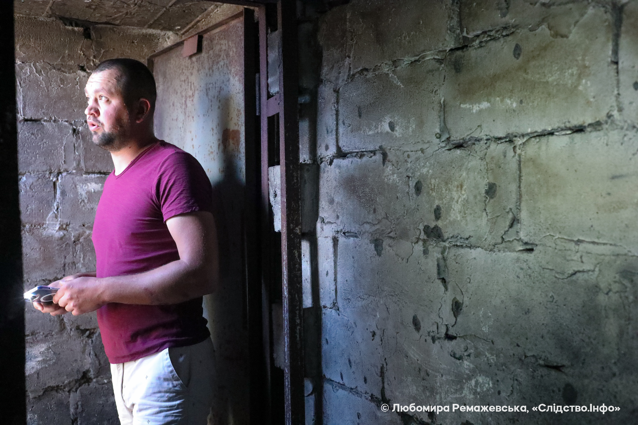 Сергій показує сліди від уламків гранати на стінах підвалу, де вони з другом переховувалися під час оточення російськими окупантами