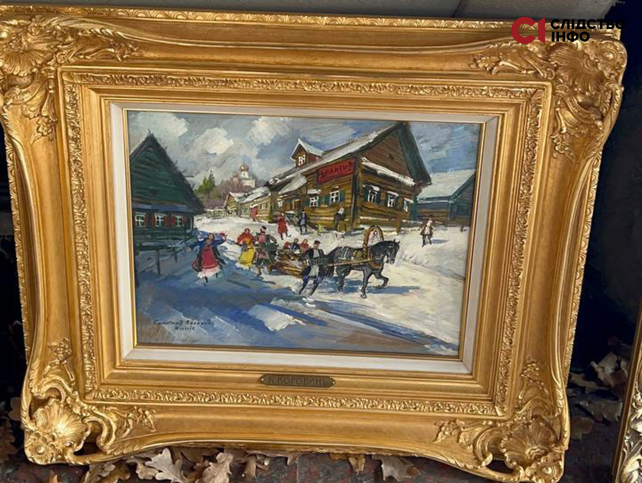 На фото картина у масивній золотій рамці: будинок, на передньому плані якого кінь з упряжкою, на землі лежить сніг