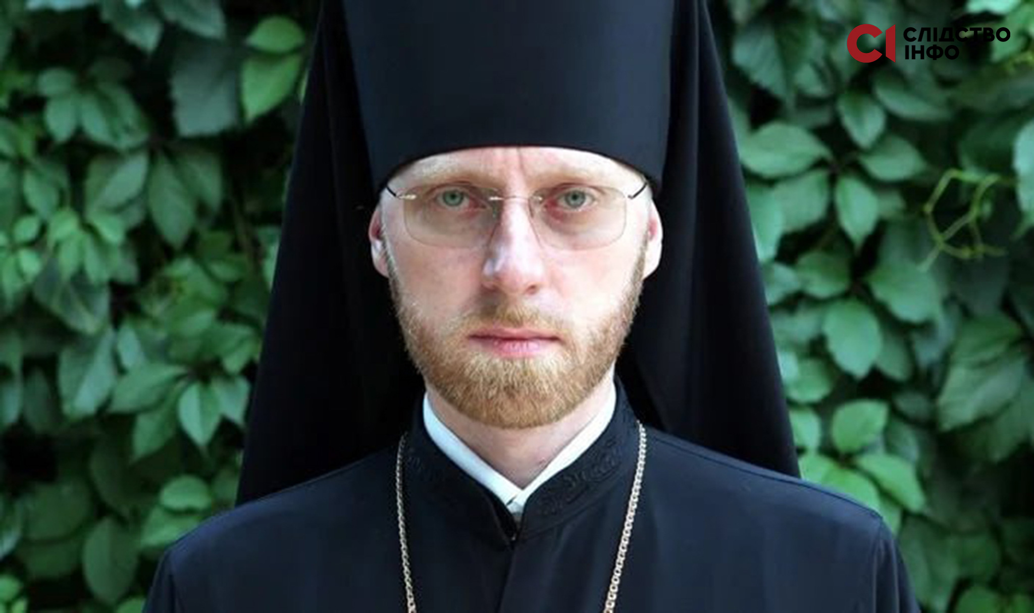 Московський священник у рясі та окулярах дивиться в об'єктив